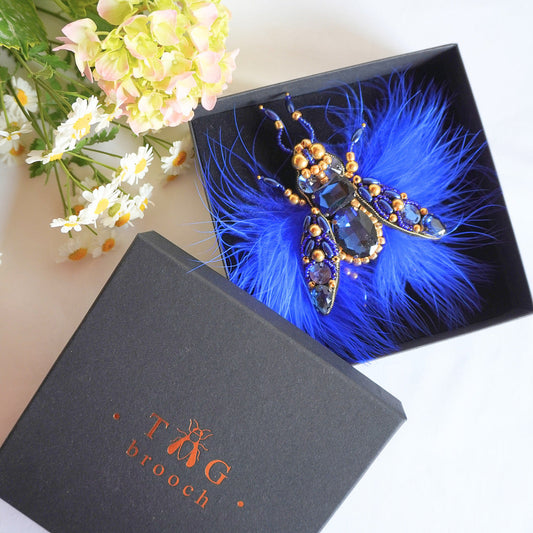 Blue feathered beaded brooch in a black box with TGbrooch branding